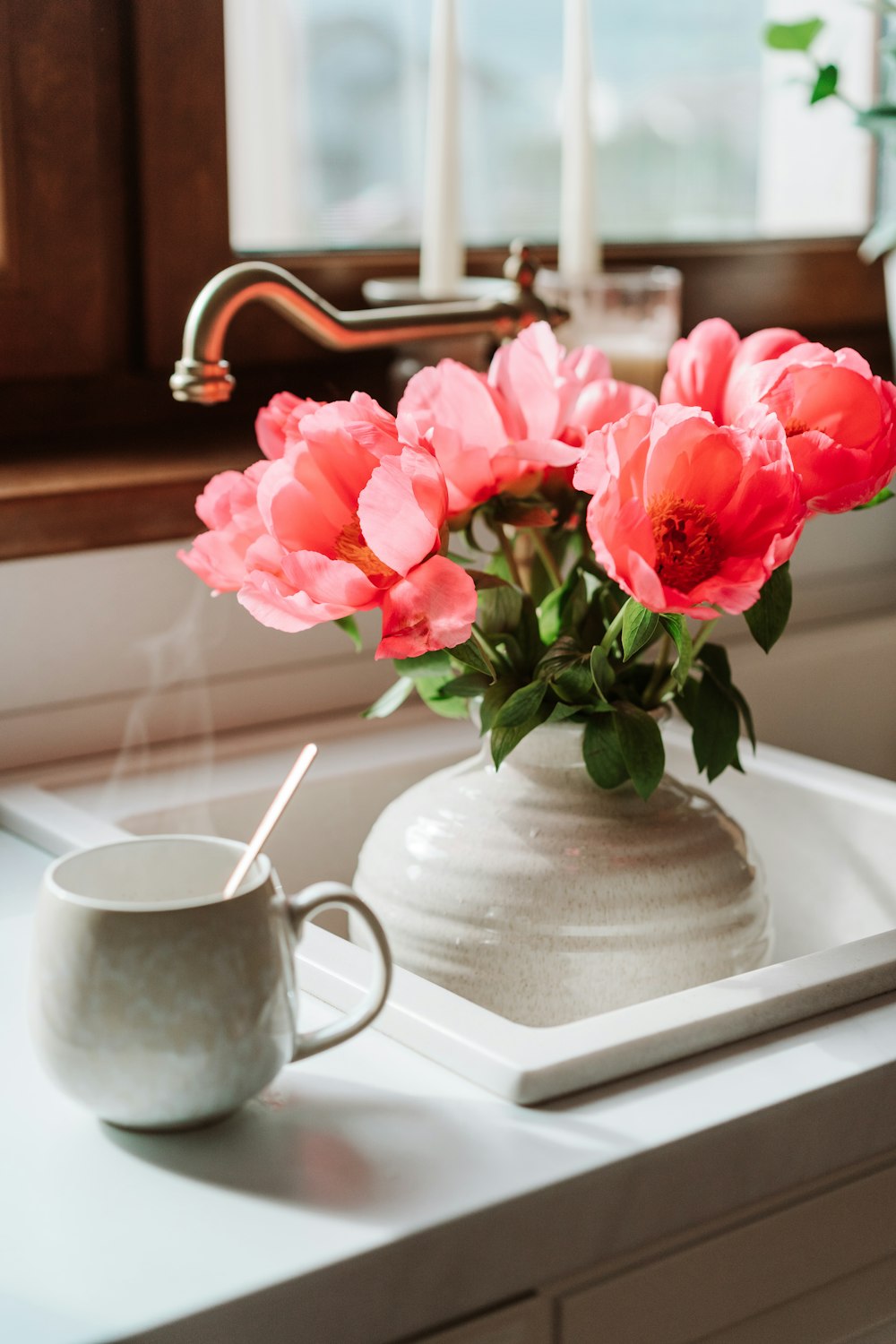 a vase of pink flowers sitting on a kitchen sink