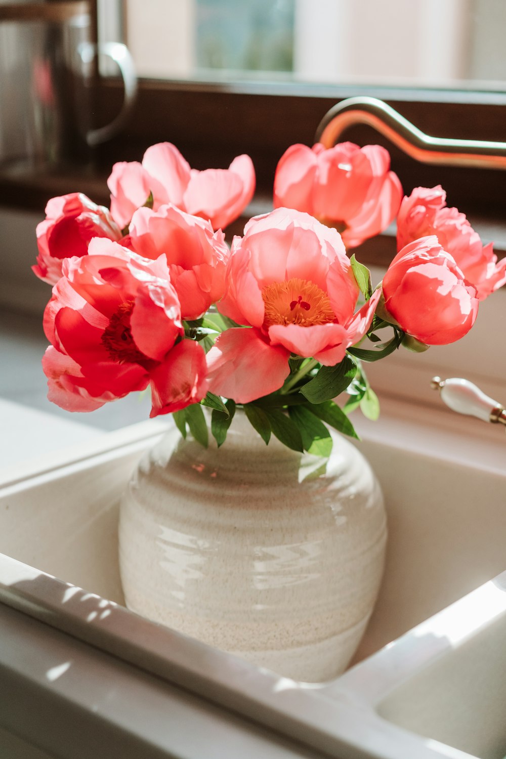 a vase filled with pink flowers sitting on a sink