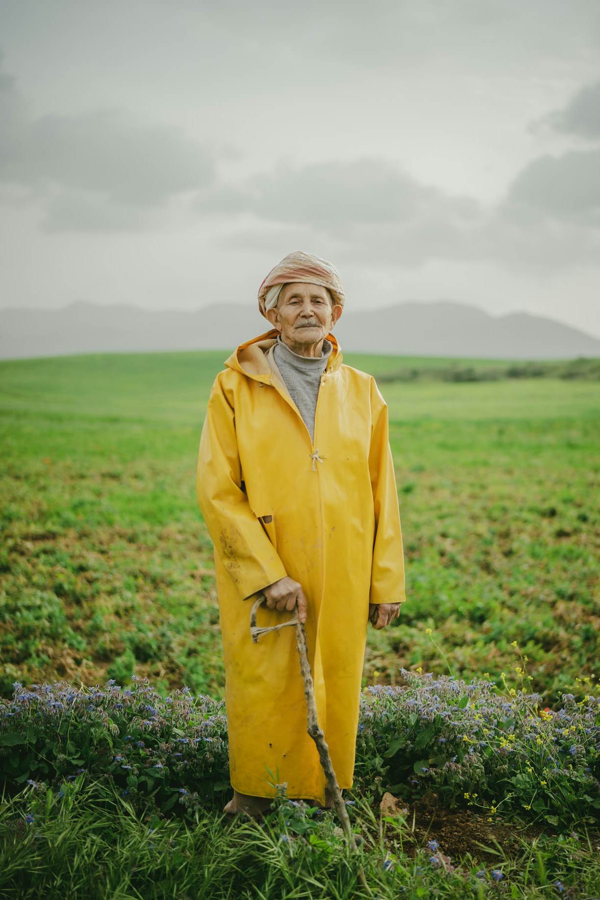 a men in a yellow raincoat standing in a field