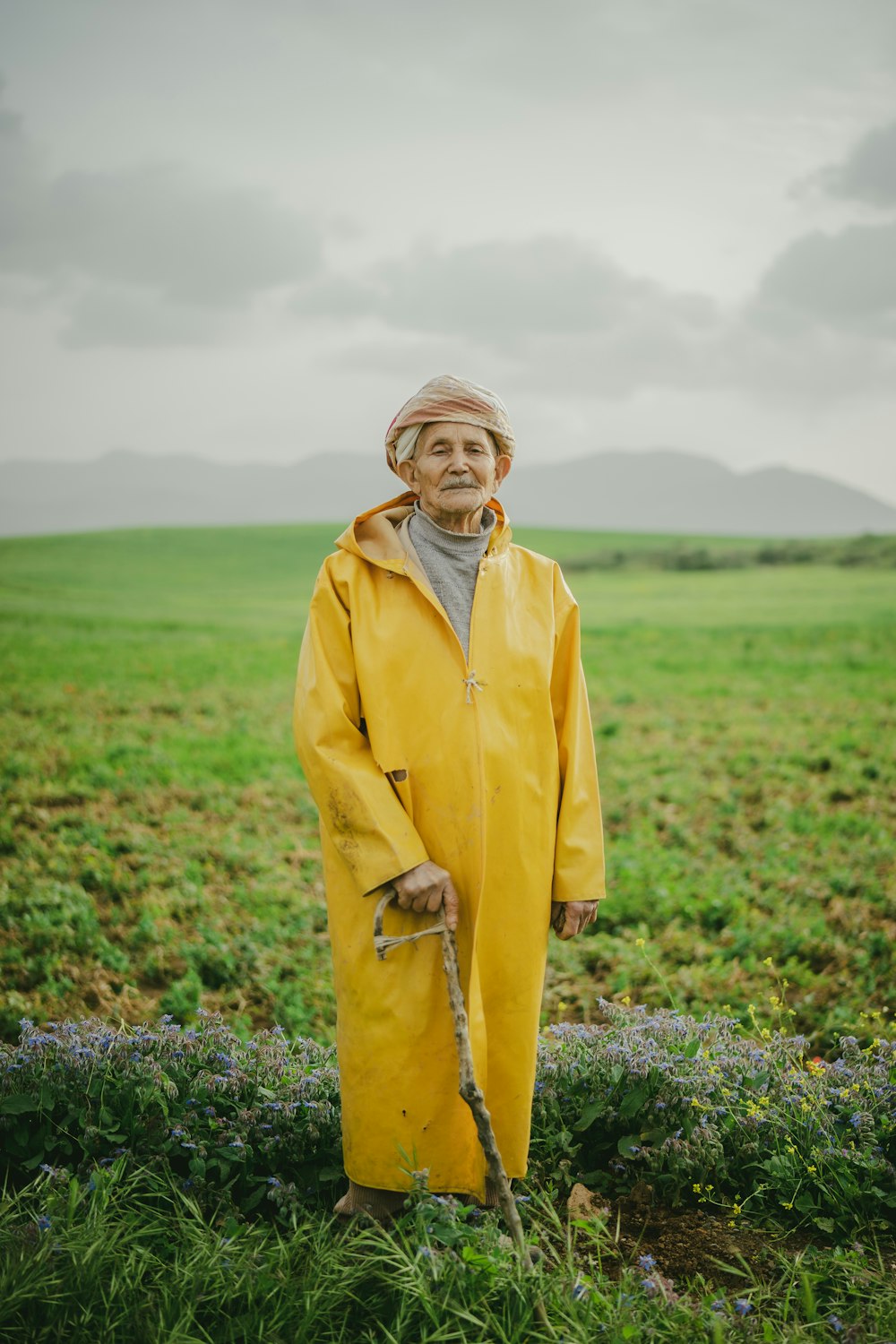 a woman in a yellow raincoat standing in a field