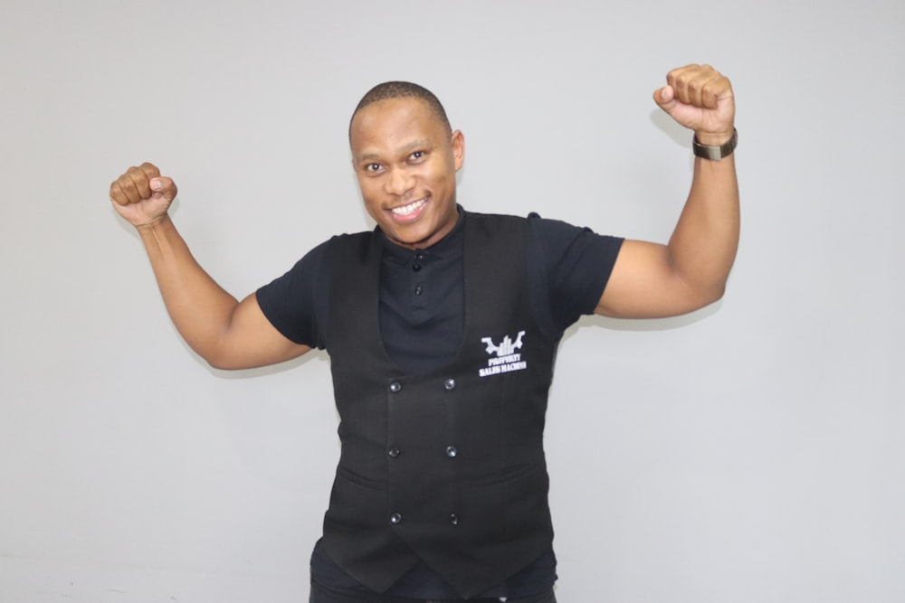 a man in a black shirt and black pants with his arms in the air