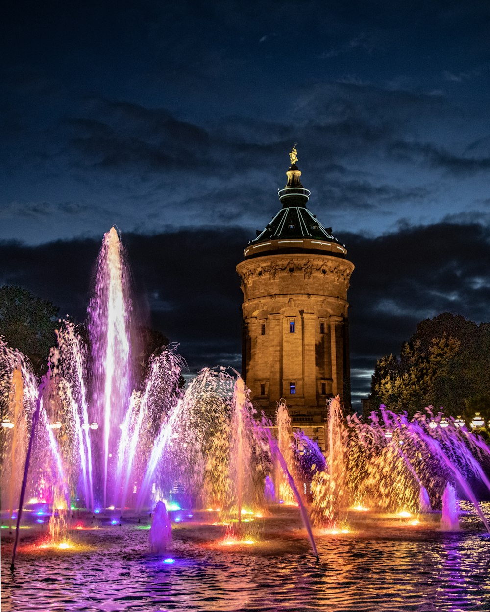 a water fountain with a clock tower in the background