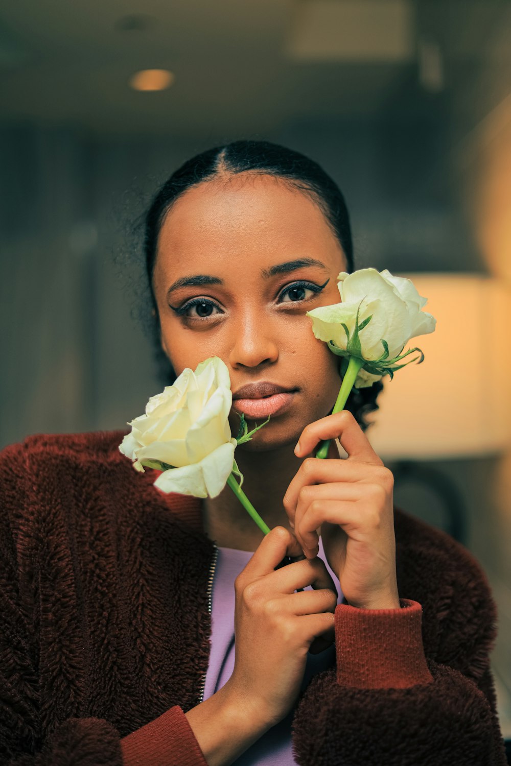 a woman holding a flower in front of her face