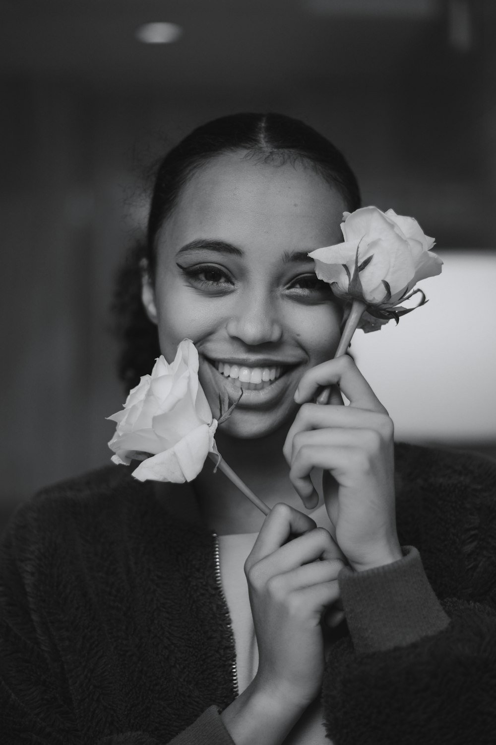 a woman smiling and holding a flower in front of her face