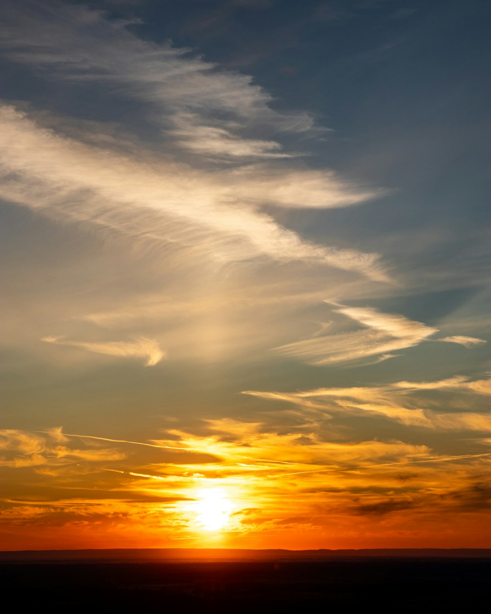 a plane flying in the sky at sunset