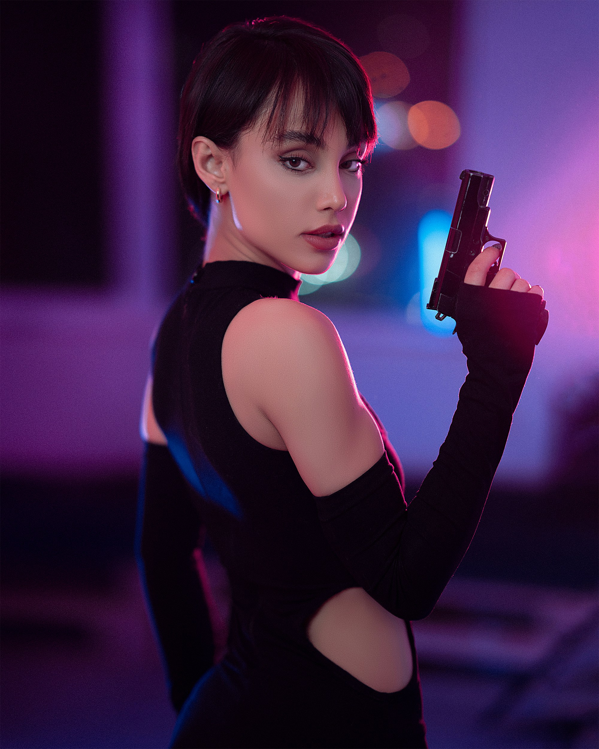 Seorang wanita bergaun hitam memegang pistol