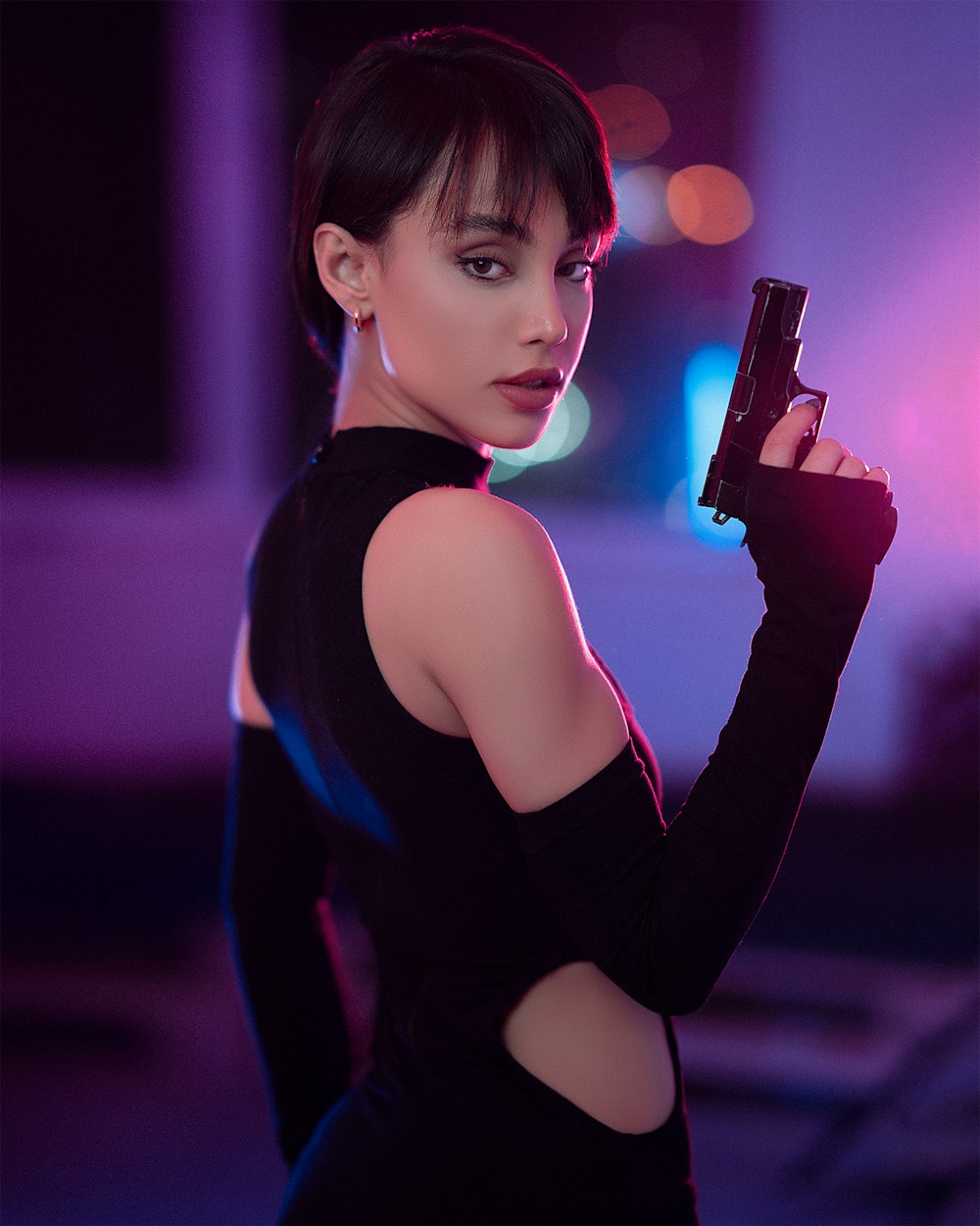 a woman in a black dress holding a gun