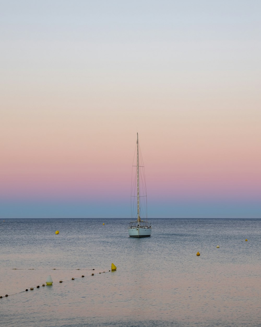 a sailboat floating in the ocean at sunset