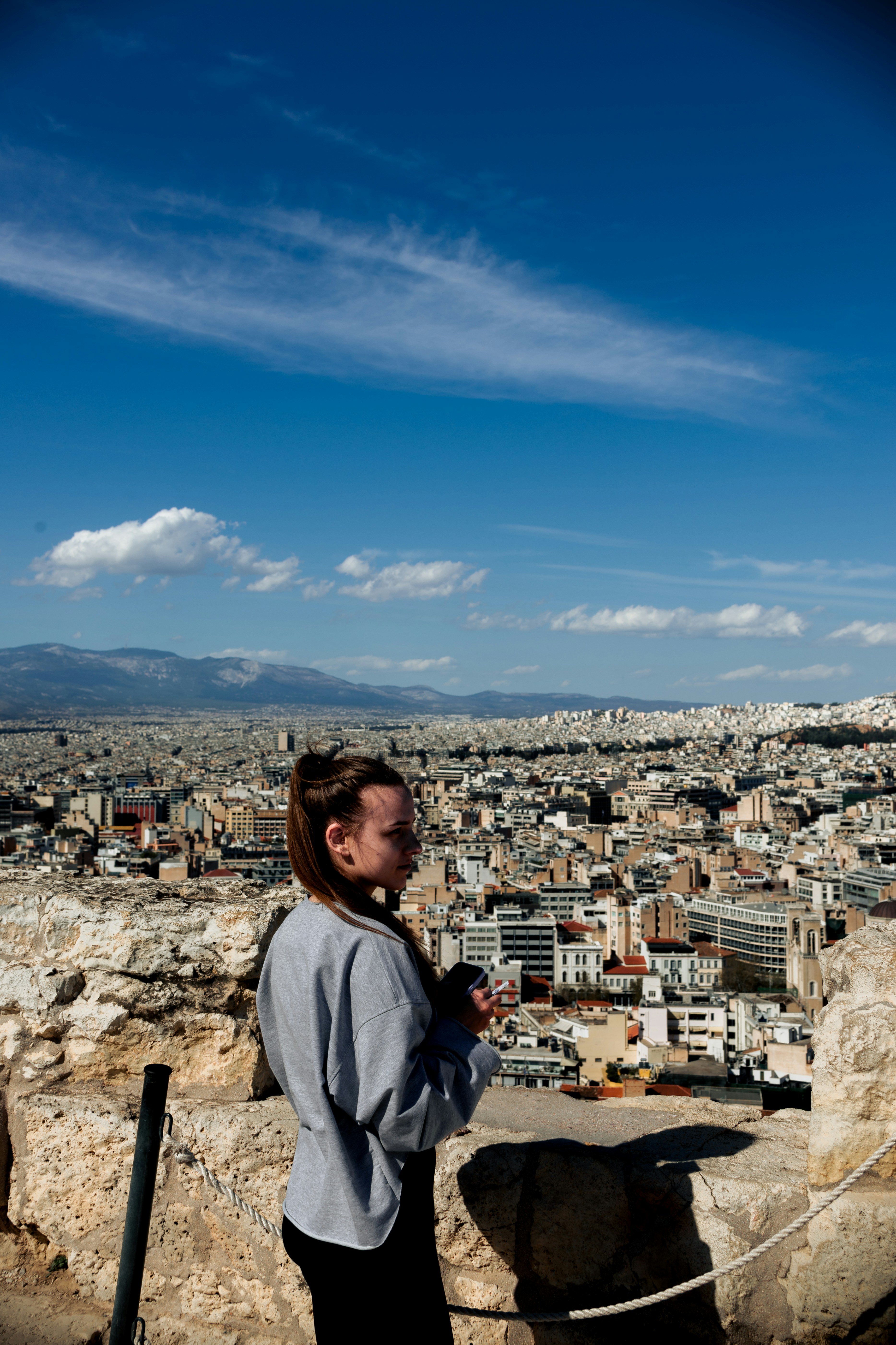 a woman standing on top of a hill next to a city