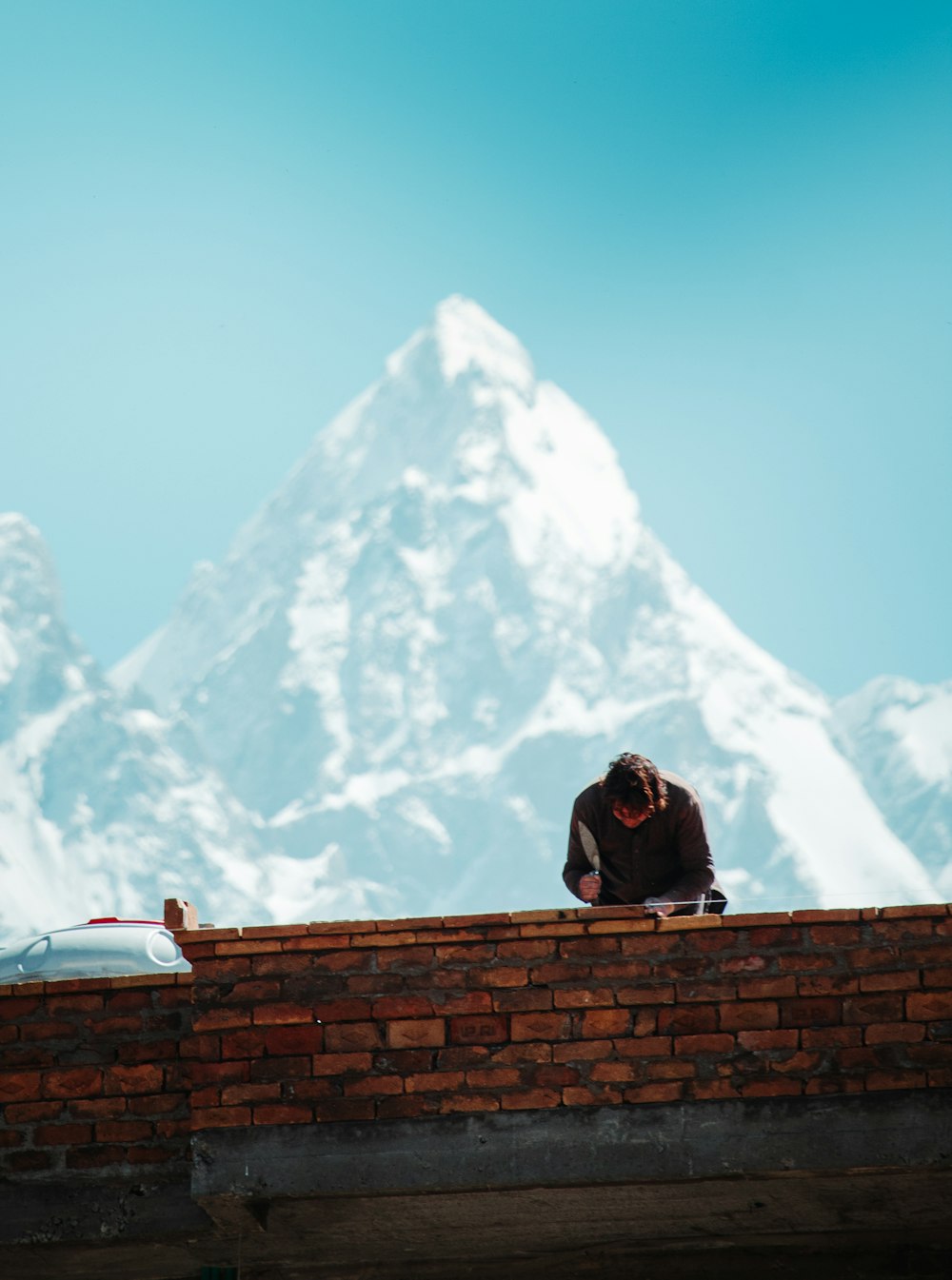 un uomo seduto sulla cima di un muro di mattoni