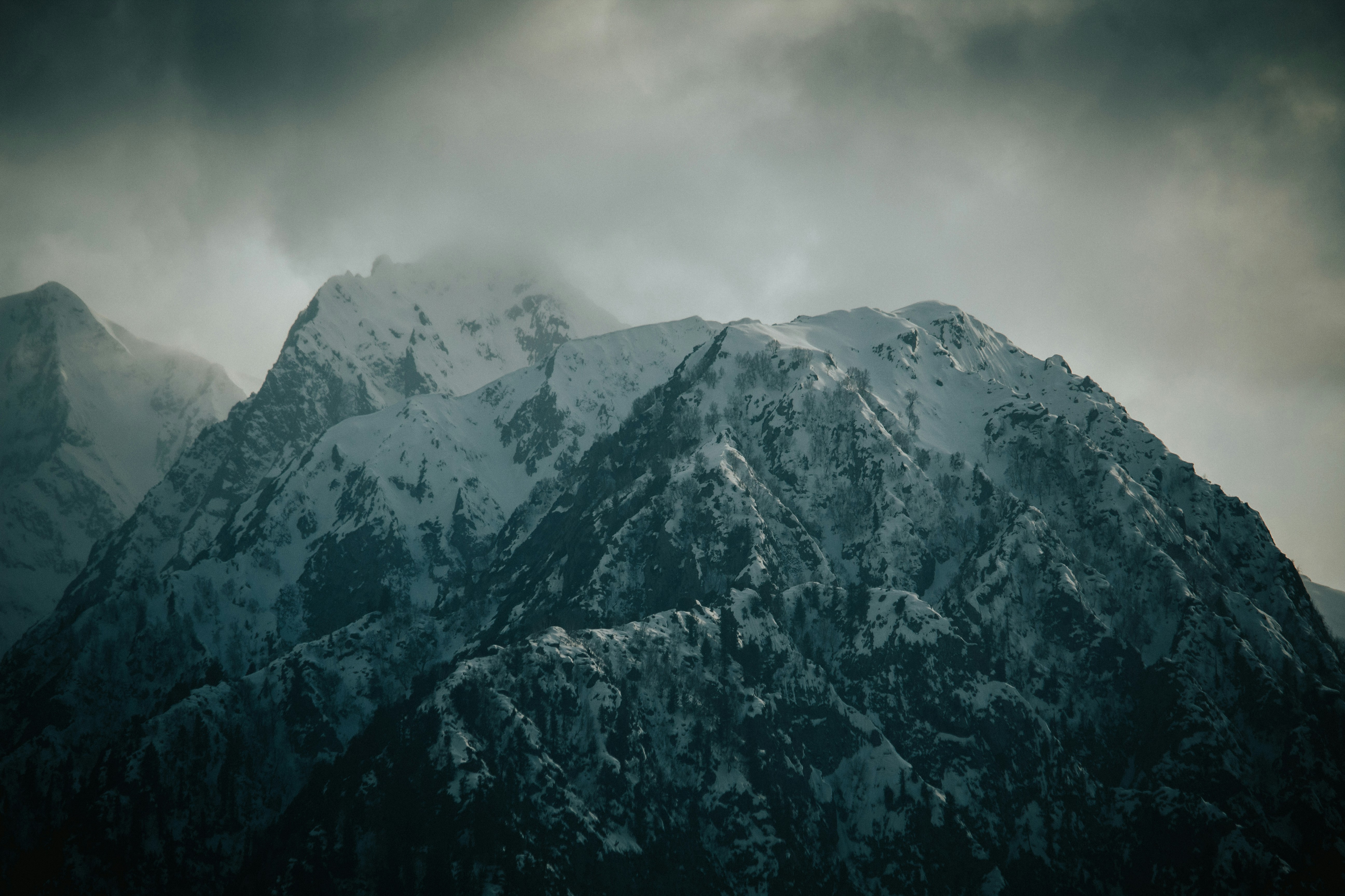 a mountain covered in snow under a cloudy sky