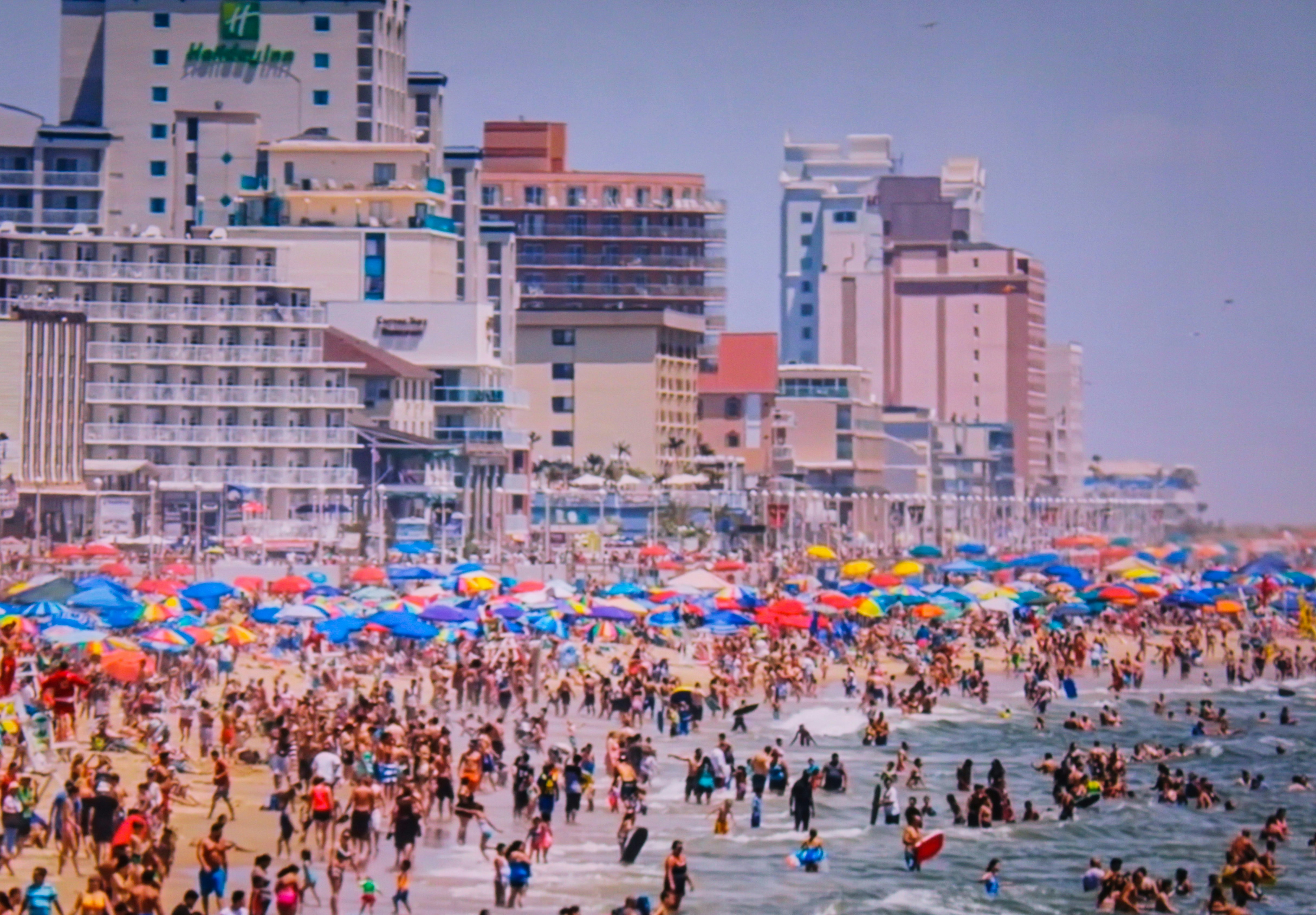 a large group of people on a beach with umbrellas