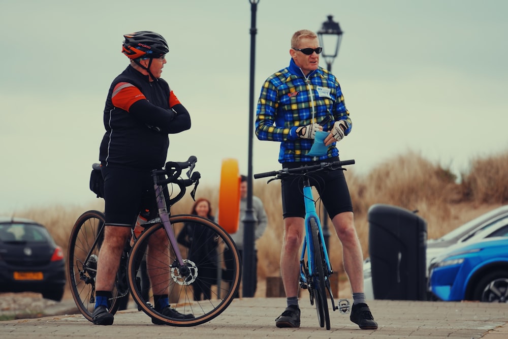 a couple of men standing next to each other with bikes