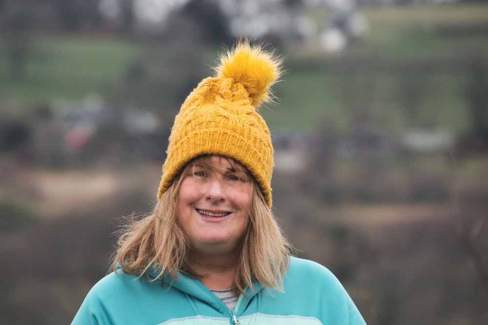 a woman wearing a yellow knit hat with a yellow pom pom