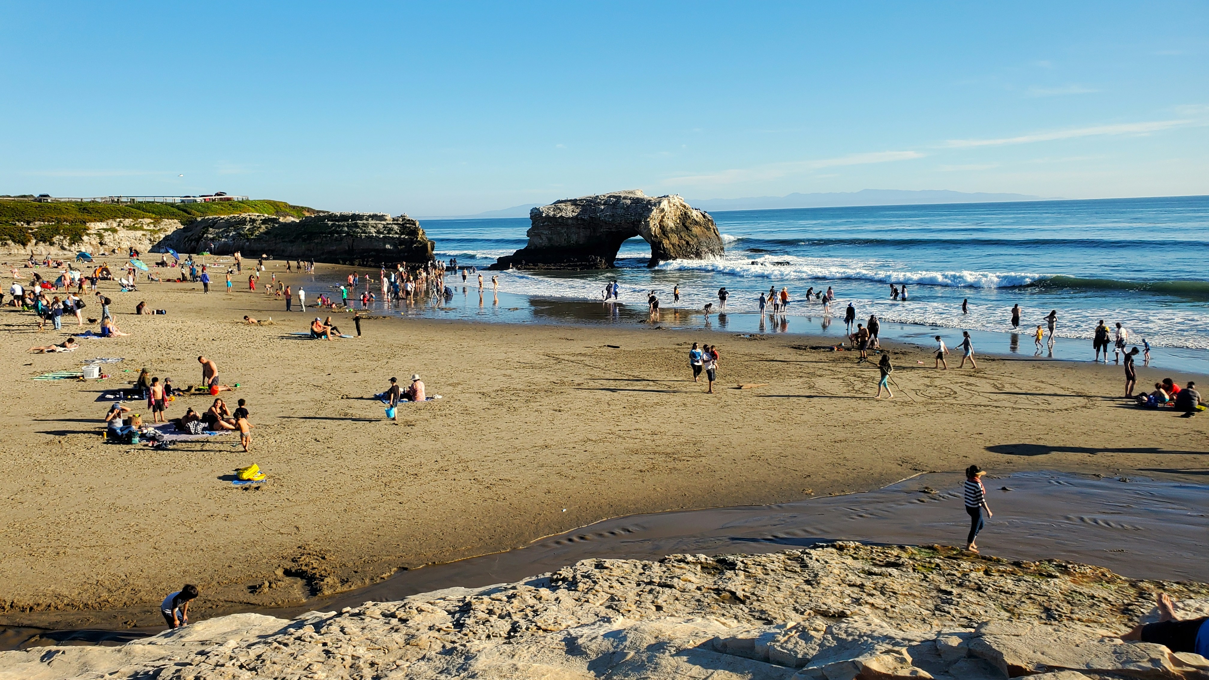 many people are on the beach near the water, Beach day at Natural Bridges in Santa Cruz California.
