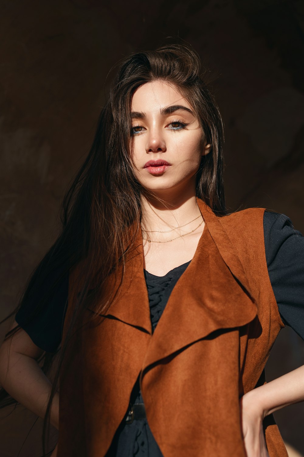 a woman with long hair wearing a brown vest