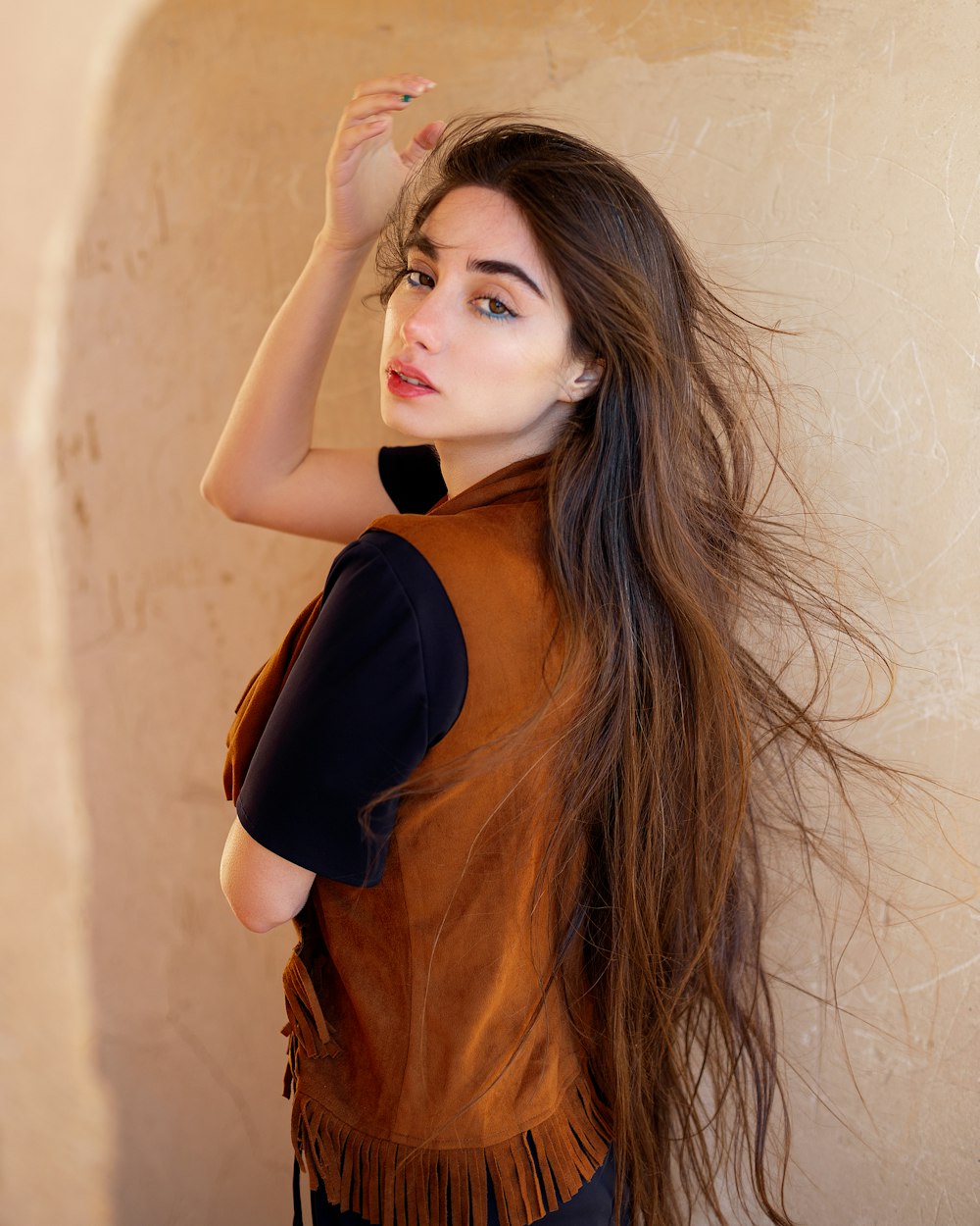 a woman with long hair standing in front of a wall