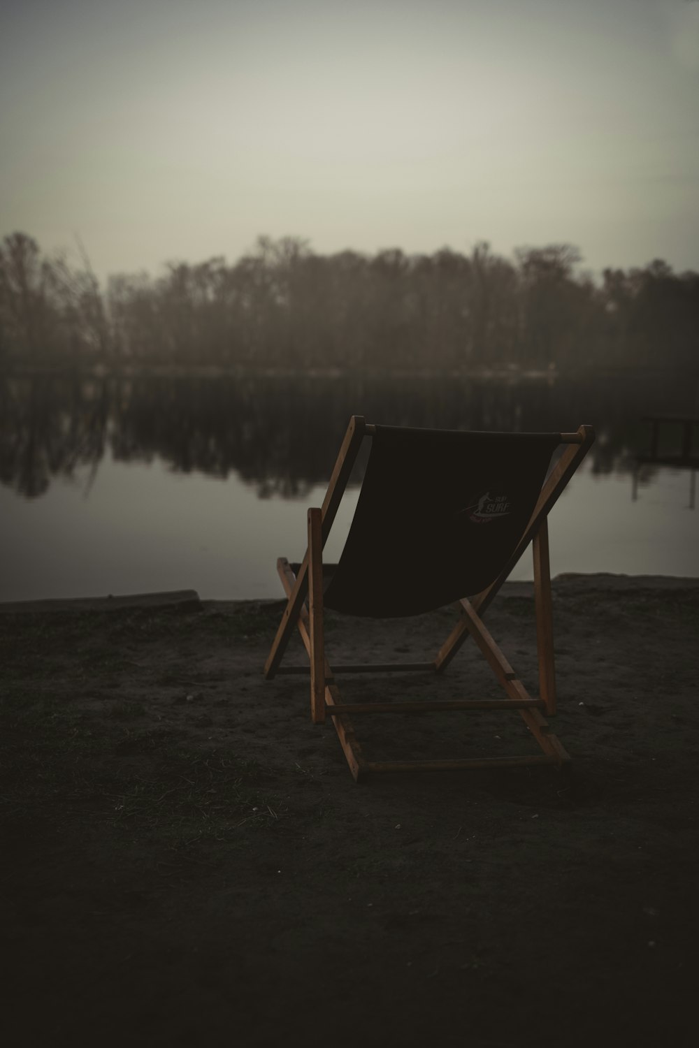 a wooden chair sitting on top of a beach next to a body of water