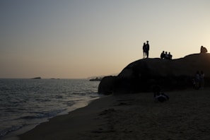 Silhouetted figures watching the sun dip below the Pembrokeshire coast, framed by rugged cliffs and big skies