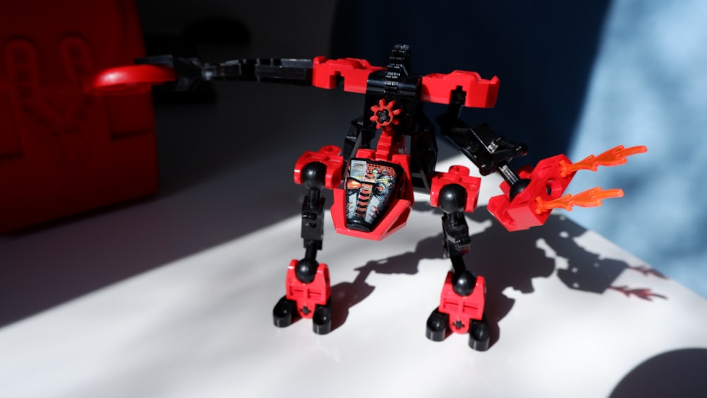 a red and black robot is on a white surface