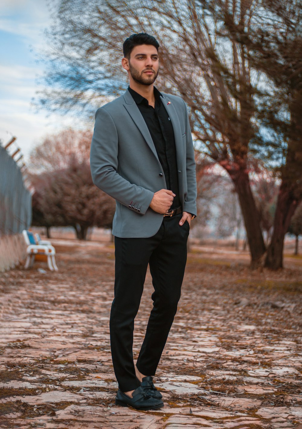 a man in a suit standing on a cobblestone road