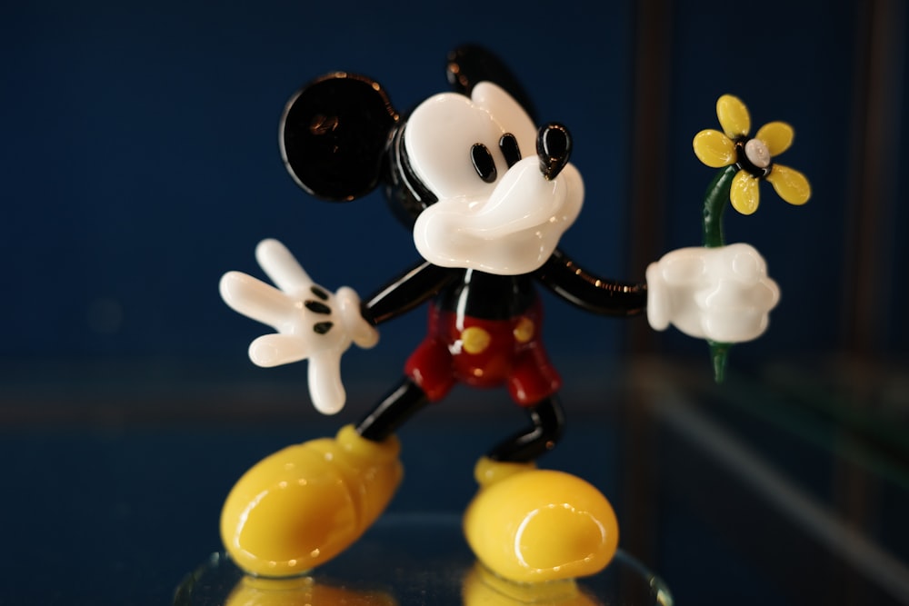 a mickey mouse figurine holding a flower