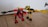 Two toy robots feature prominently, crafted from colorful plastic pieces. One is predominantly red and black, with a shield-like emblem on its chest and a small fire piece in its hand. The other is primarily yellow and black, with extended arms resembling mechanical forks. They stand on a wooden floor with a white wall and part of a door hinge visible in the background.