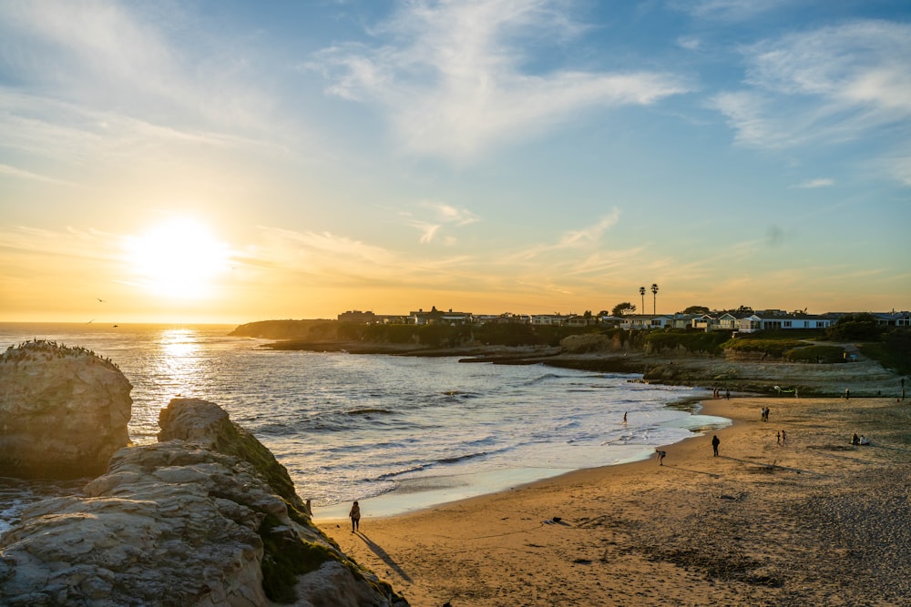 the sun is setting over a beach with people on it