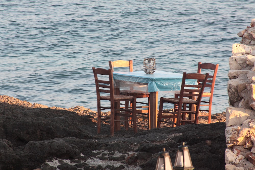 a table and chairs sitting on a rocky shore