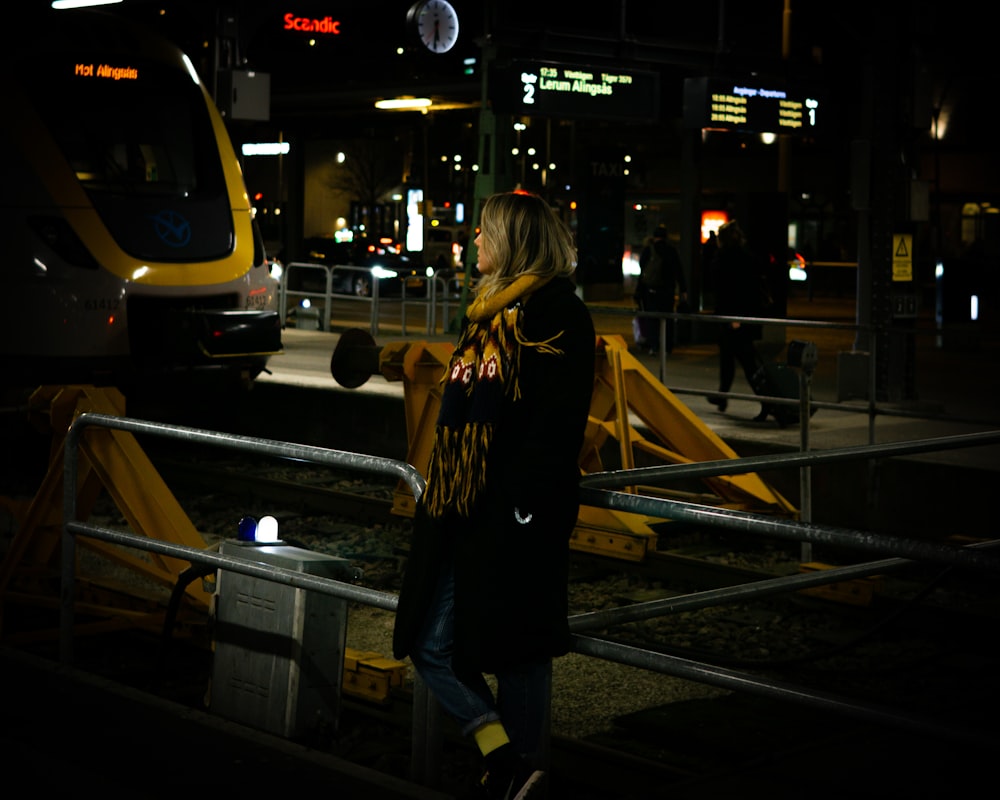 a woman standing on a train platform at night