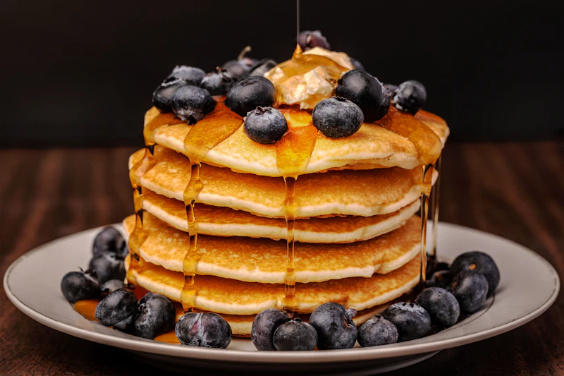 Pila de pancakes con arándanos y miel de maple