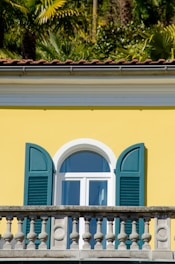 a yellow building with blue shutters and a clock