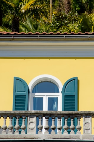 a yellow building with blue shutters and a clock