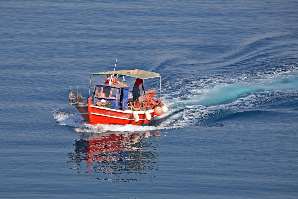 a red and white boat in the middle of the ocean
