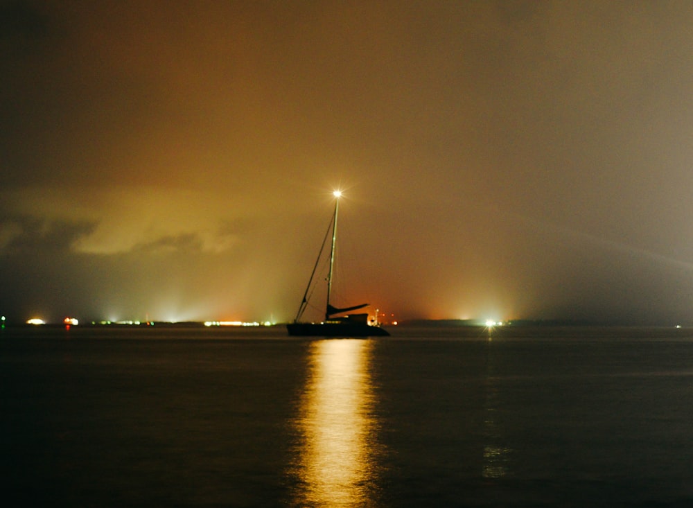 a sailboat in the water at night time