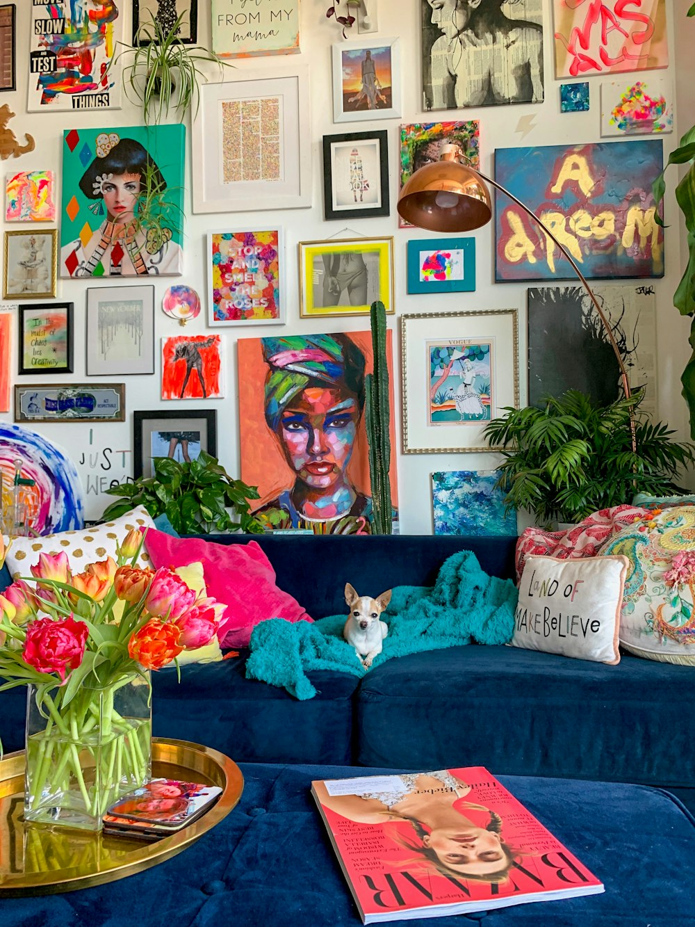 Un salon rempli d’un canapé bleu et beaucoup de photos sur le mur
