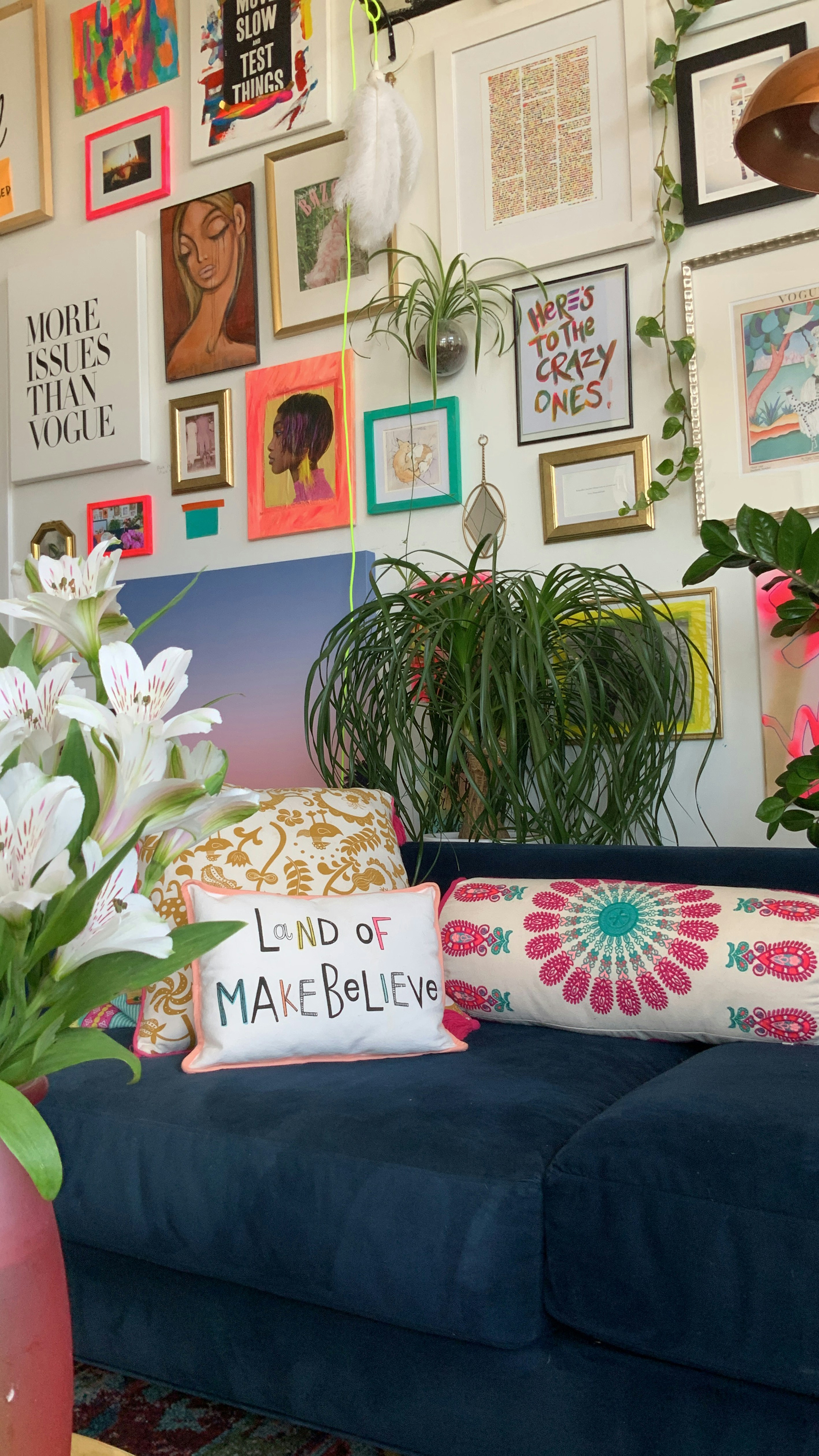 Maximalist gallery wall and colorful home decor with lots of plants and a ponytail palm