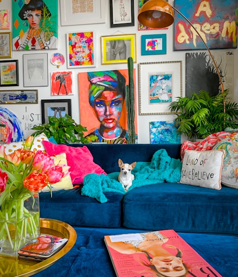 a living room filled with a blue couch and lots of pictures on the wall