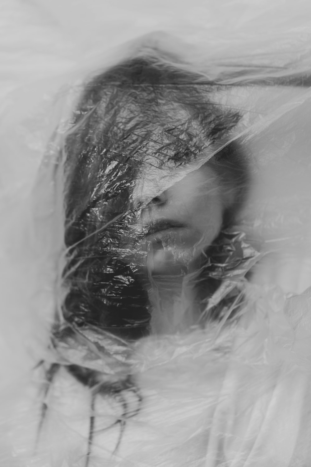 a black and white photo of a woman's face covered in plastic