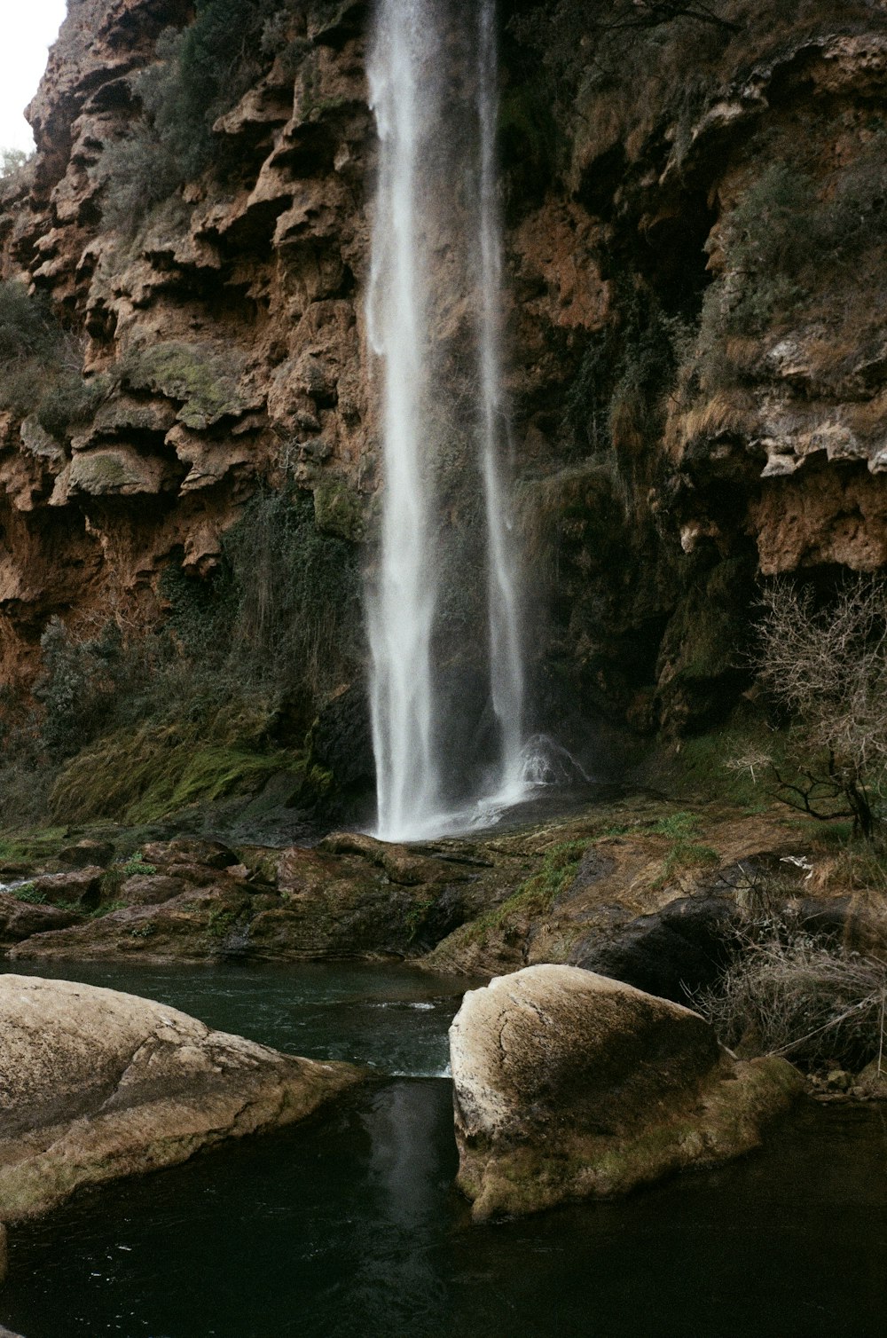 a large waterfall is in the middle of a rocky area