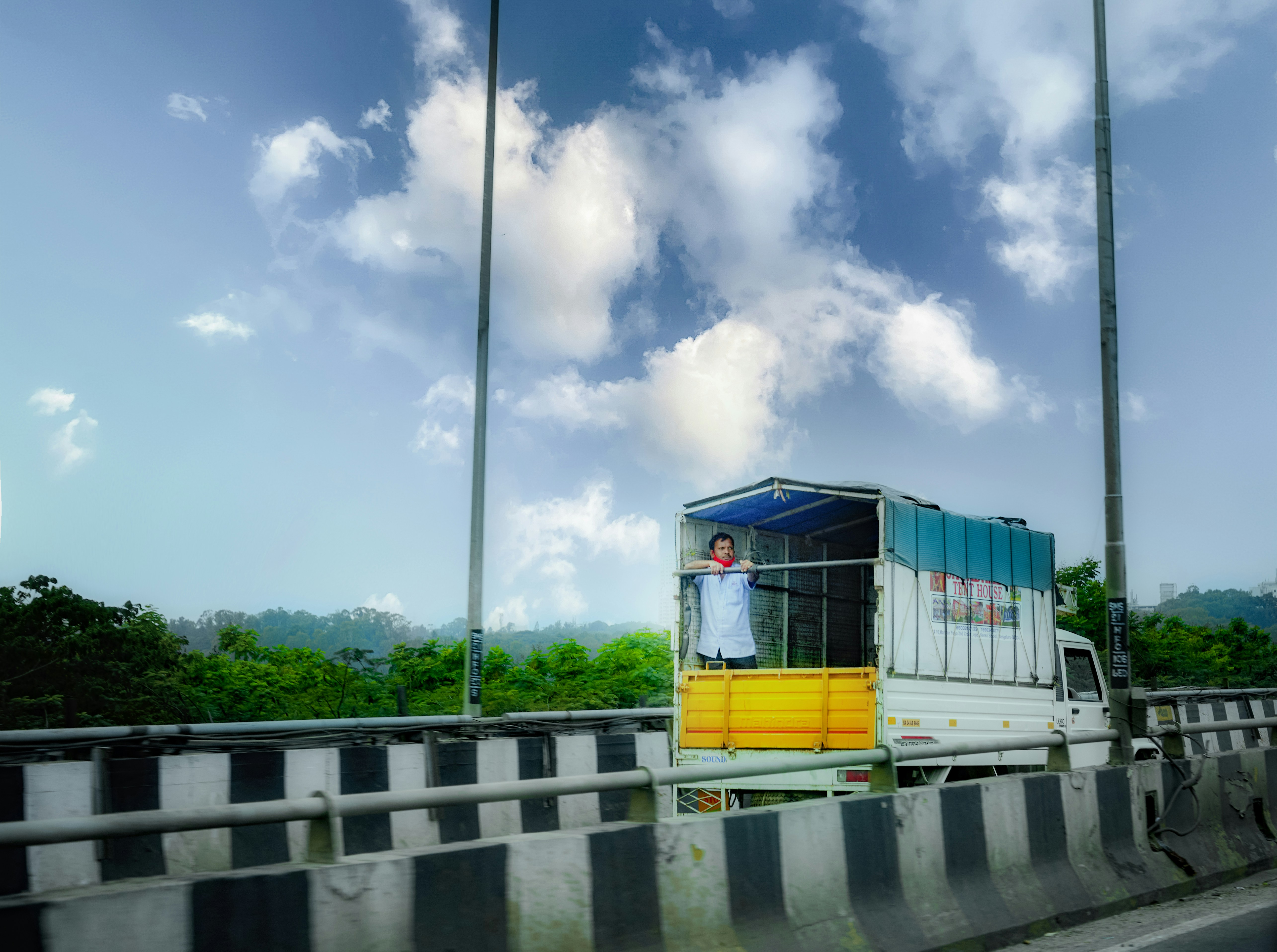a truck driving down a highway with a man in the back of it
