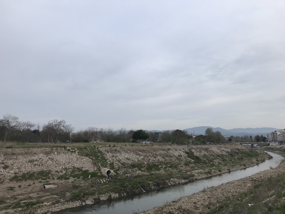 a river running through a dry grass covered field