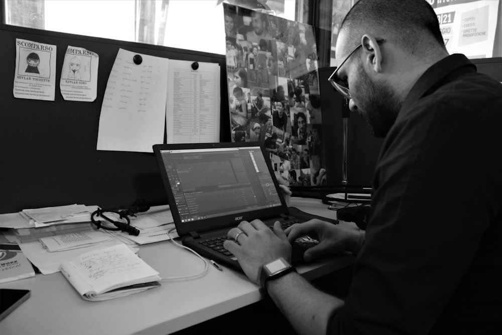 a man sitting at a desk using a laptop computer