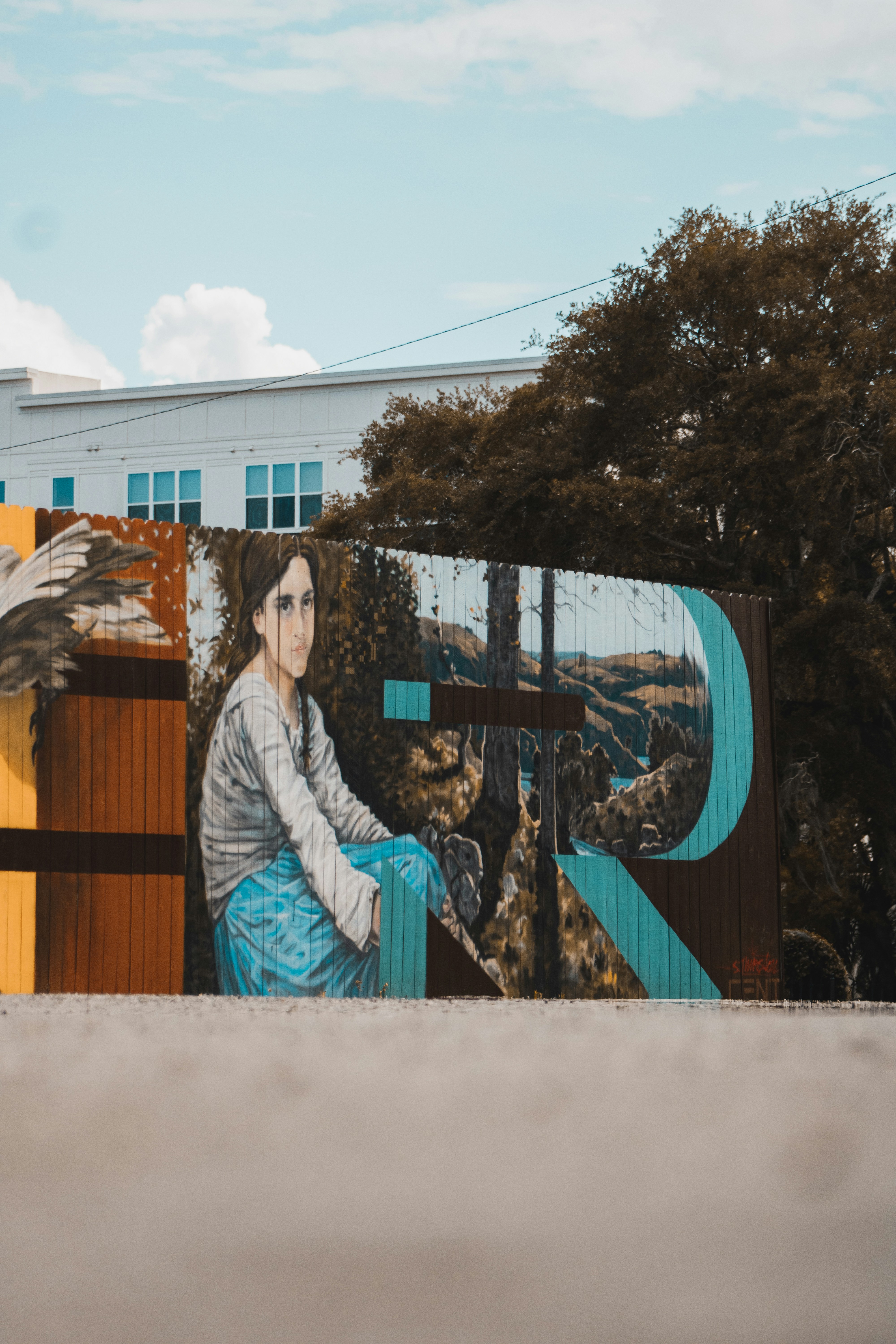 seorang wanita duduk di bangku di depan mural