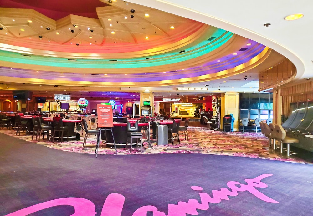 a brightly lit casino room with tables and chairs