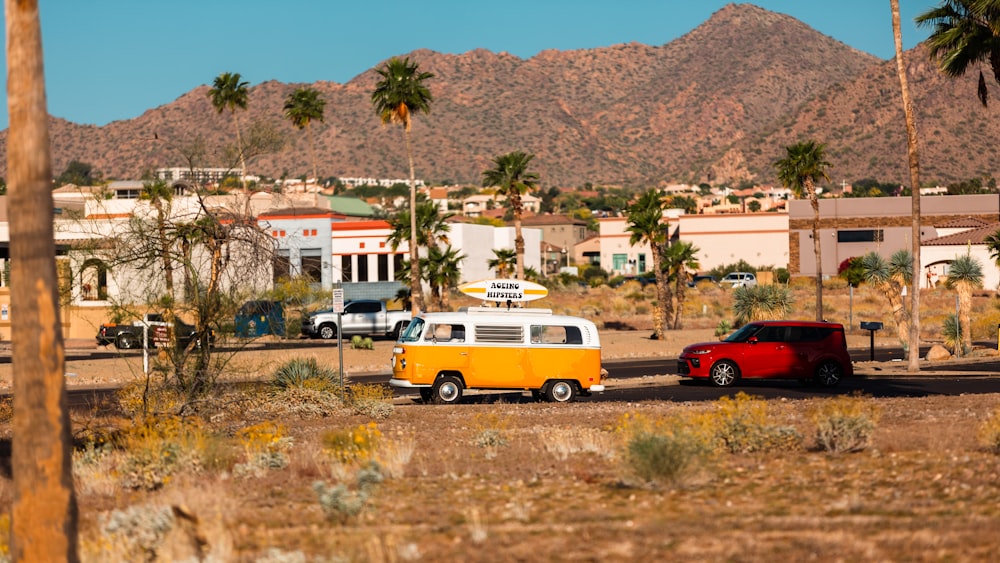 a yellow and white van parked next to a red car