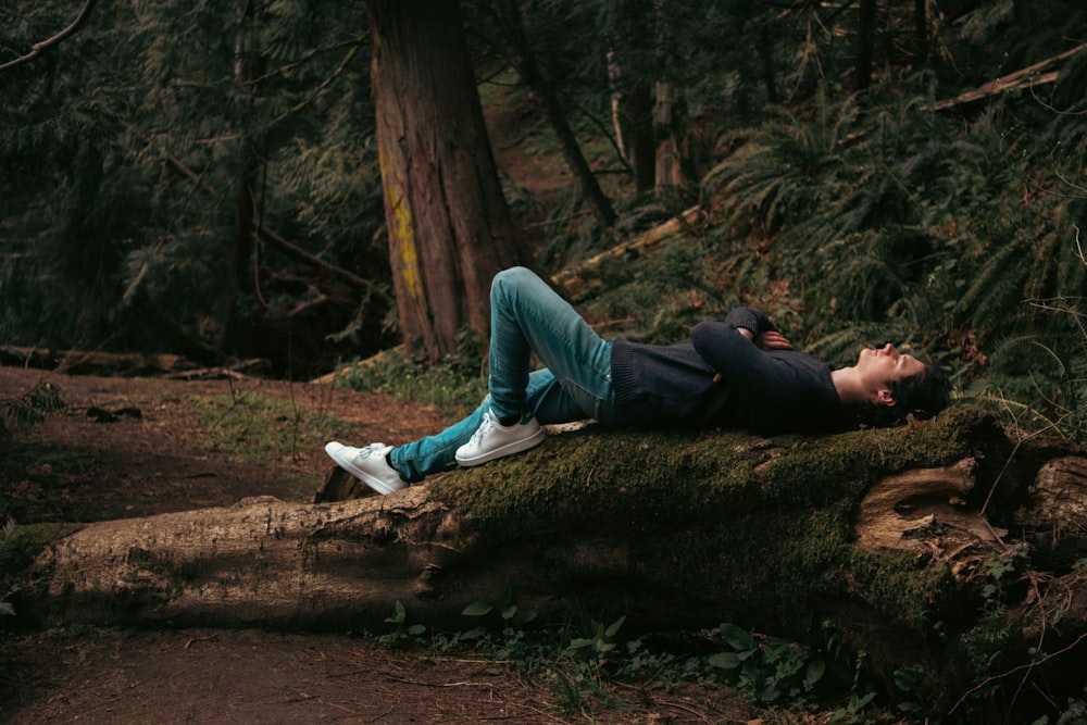 a person laying on a log in a forest