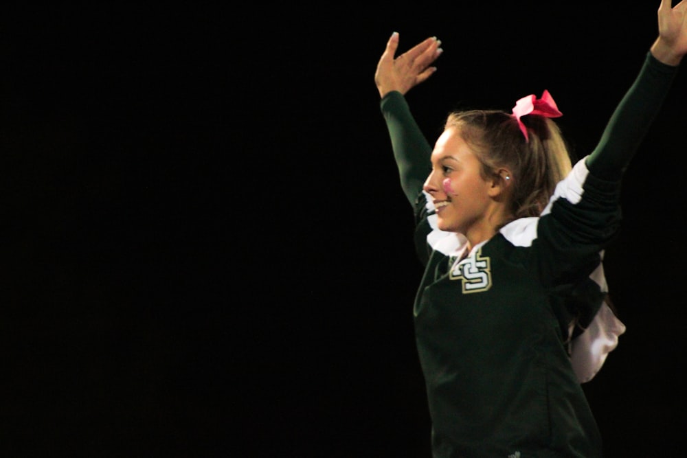 a girl in a cheerleader uniform raising her arms in the air