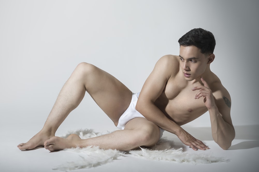 a man in a white underwear laying on a white rug