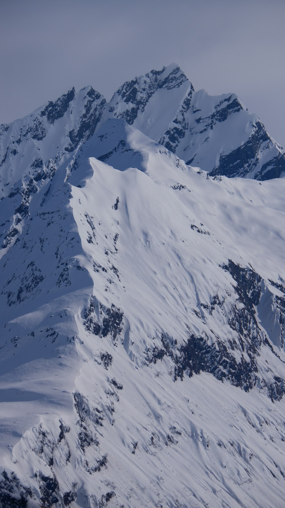 a large mountain covered in snow with a sky background